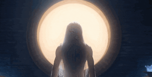 a woman with long hair is standing in front of a large light