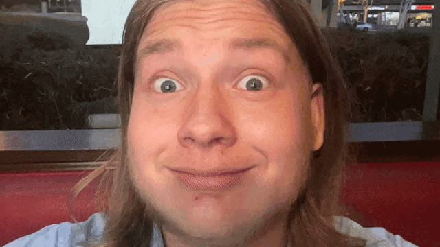 a man with long hair making a funny face in front of a mcdonald 's