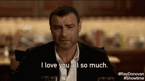 a man in a suit is sitting at a table with a glass of wine and says `` i love you all so much '' .