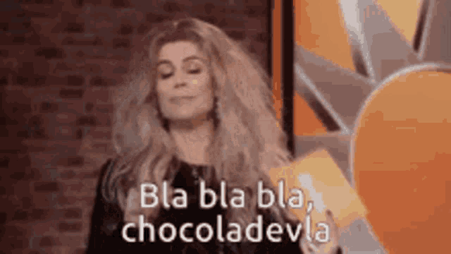 a woman is standing in front of a brick wall with her eyes closed and says bla bla bla , chocoladevila .