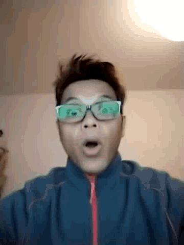 a man wearing glasses and a blue jacket is making a funny face
