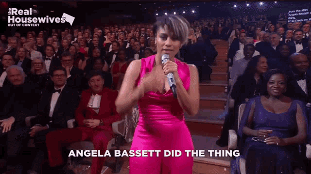 angela bassett sings into a microphone in front of a crowd