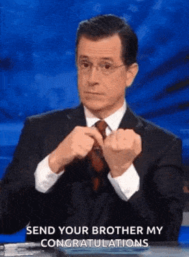 a man in a suit and tie is making a funny face while sitting at a table .