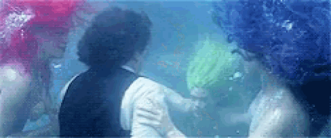 a man and two mermaids are swimming in a pool