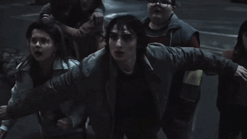 a group of children are standing in a dark room and one of them has glasses on