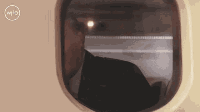 a man is looking out of a window with a wpl logo on the bottom right