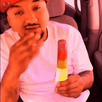 a man wearing a red hat is eating a popsicle