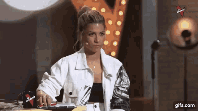 a woman in a white jacket is sitting at a table .