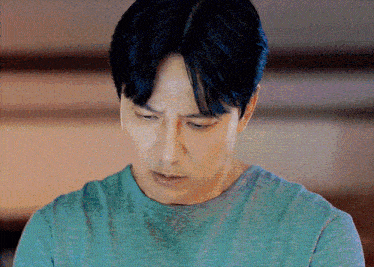 a close up of a man 's face with a blue shirt on