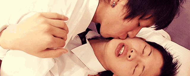 a man kisses another man on the cheek while laying on a bed