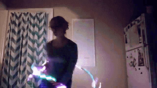 a woman is spinning a hula hoop in a dark room