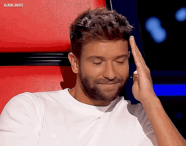a man with a beard is sitting in a chair with his hand on his forehead and the words albor.ngifs on the top