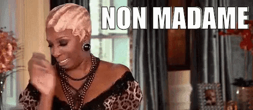 a woman in a leopard print dress is dancing in a living room with the words `` non madame '' written on the screen .
