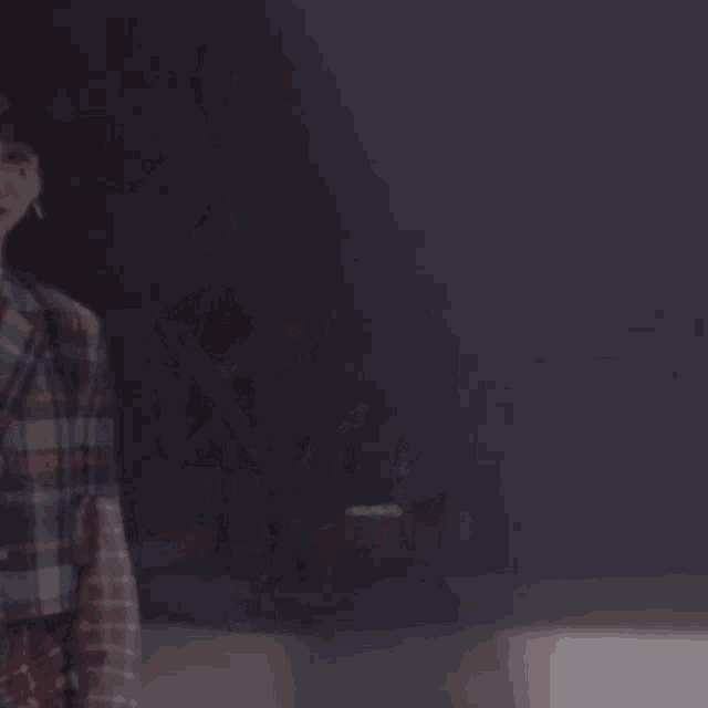 a man in a plaid jacket and tie is making a heart with his hands .