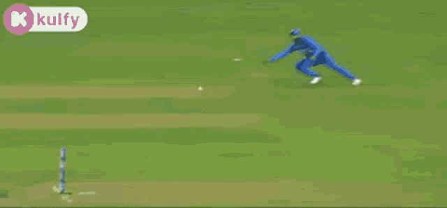 a man in a blue suit is laying on the ground on a cricket field
