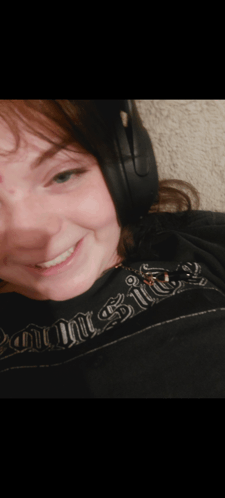 a woman wearing headphones is smiling and wearing a shirt that says ' knight 's ' on it