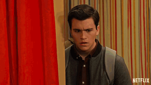 a man standing in front of a red curtain with a netflix logo