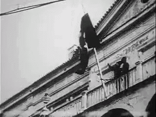 a black and white photo of a man hanging from a balcony .