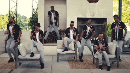 a group of men wearing baseball jerseys with the letter k on them are dancing in front of a fireplace