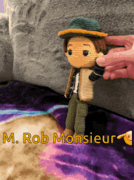 a person holding a crocheted doll with the name rob monsieur on the bottom