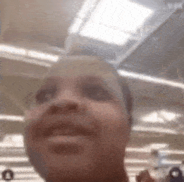 a close up of a person 's face in a store with a ceiling light in the background .