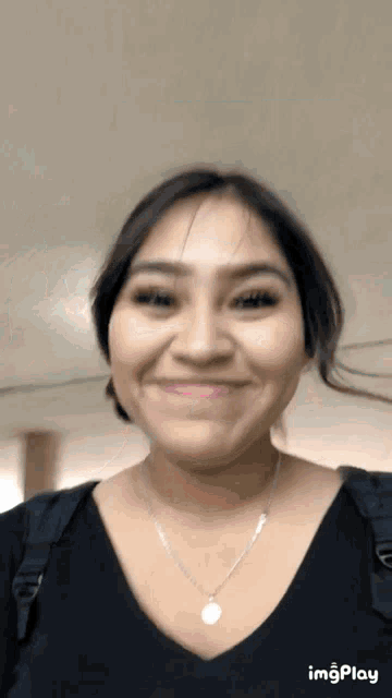 a woman wearing a black shirt and a silver necklace is smiling for the camera