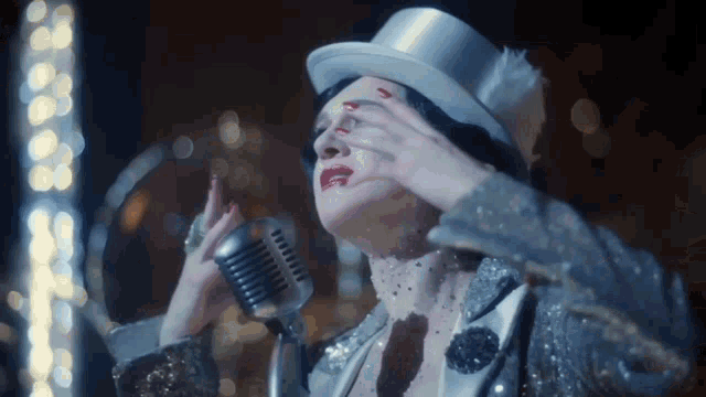 a woman singing into a microphone with her hand over her face