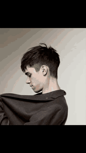 a young man with a very short haircut is looking down at something