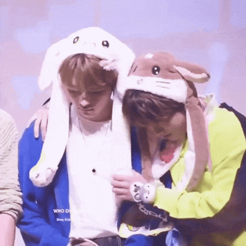 two young men wearing bunny hats are sitting next to each other .
