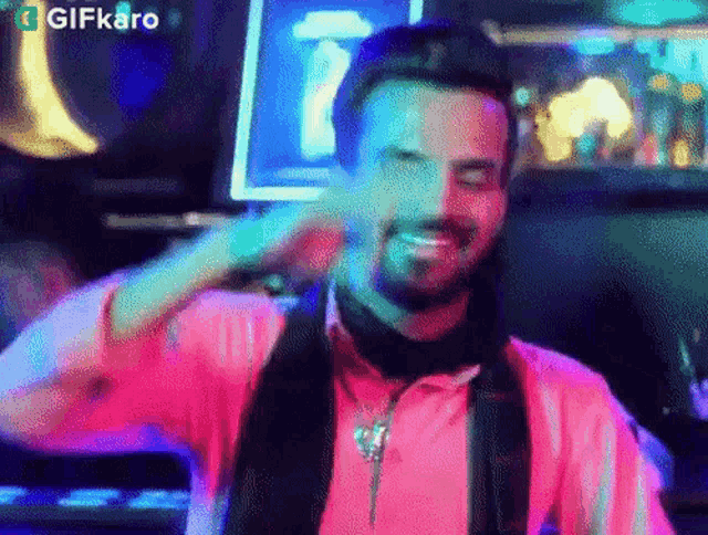 a man with a beard is wearing a pink shirt and scarf and smiling .