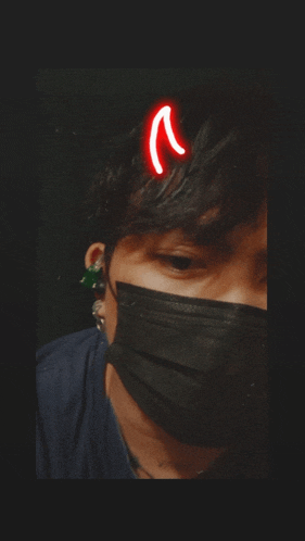 a person wearing a black mask with a red devil horn on their head