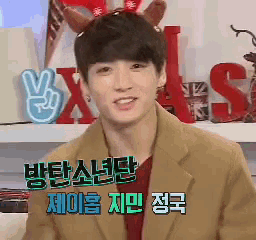 a young man wearing a reindeer headband is smiling in front of a sign that says ' x '