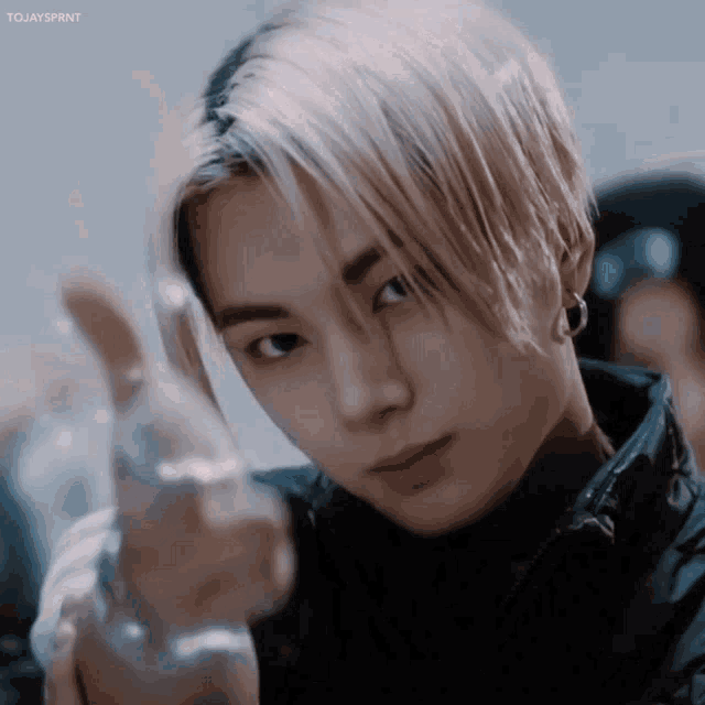 a young man with blonde hair is pointing at the camera