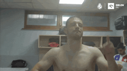 a shirtless man in a locker room with orlen oil written on the wall