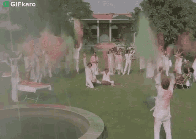 a group of people are playing with colored powder in a park with a gifkaro watermark