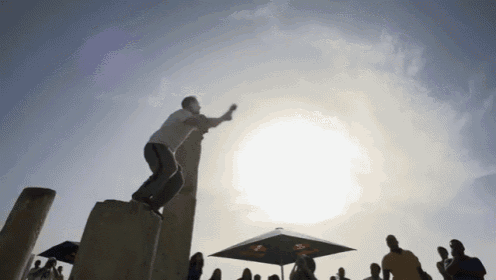 a group of people are standing under umbrellas and a man is standing on a pole