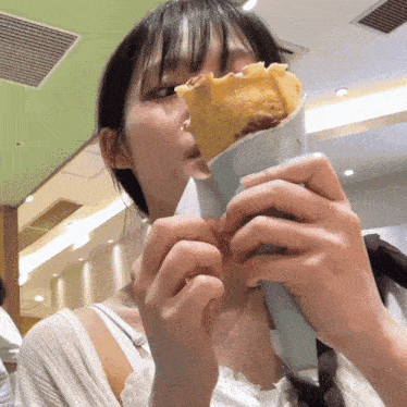 a young woman is eating a crepe in a restaurant