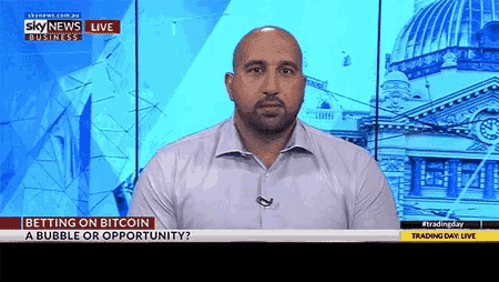 a man is sitting in front of a screen that says sky news business live