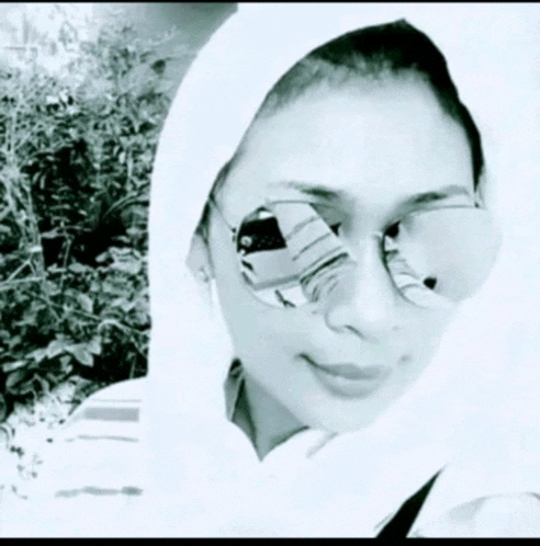 a black and white photo of a woman wearing a hijab and sunglasses