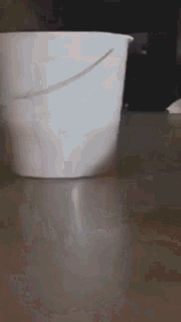 a white bucket is sitting on a table with a black background