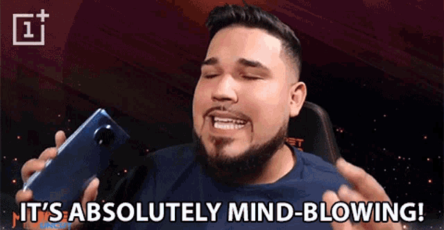 a man is holding a cell phone and says it 's absolutely mind-blowing