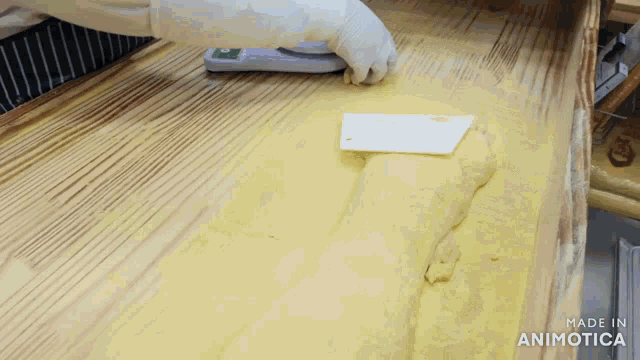a person is measuring a piece of dough on a scale with the words made in animotica visible in the corner