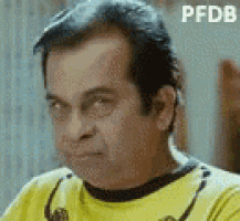 a man in a yellow shirt is making a funny face and looking at the camera .
