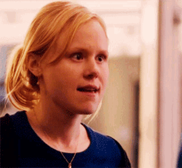 a woman with blonde hair is wearing a black shirt and a gold necklace