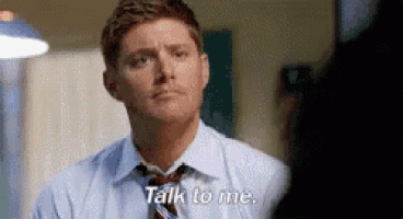 a man in a suit and tie is talking to another man and says `` talk to me '' .