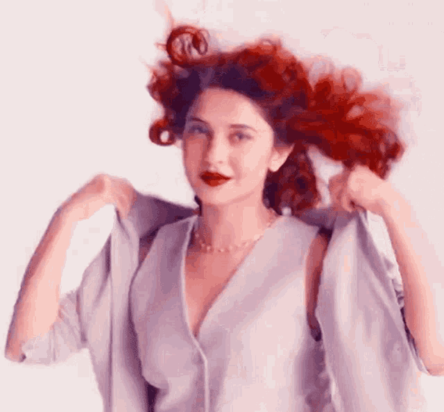a woman with red hair is wearing a purple dress and a jacket .