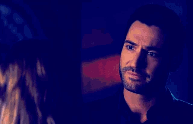 a woman is standing next to a man in a dark room looking at him .