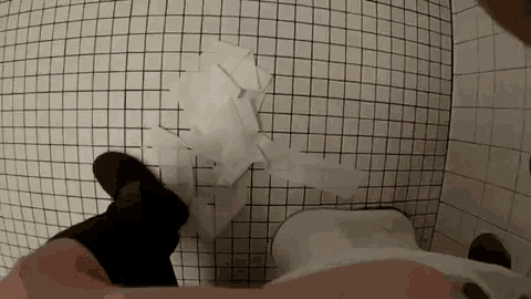 a person is sitting in a toilet with a pile of toilet paper on the floor