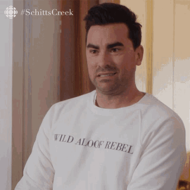 a man is wearing a white sweater that says wild aloof rebel