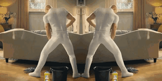 a man standing in a living room with a bottle of mr. clean